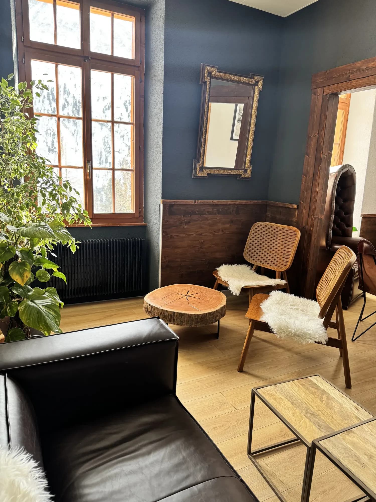 Le petit salon aux murs bleu nuit, fauteuils cannés et table en rondin